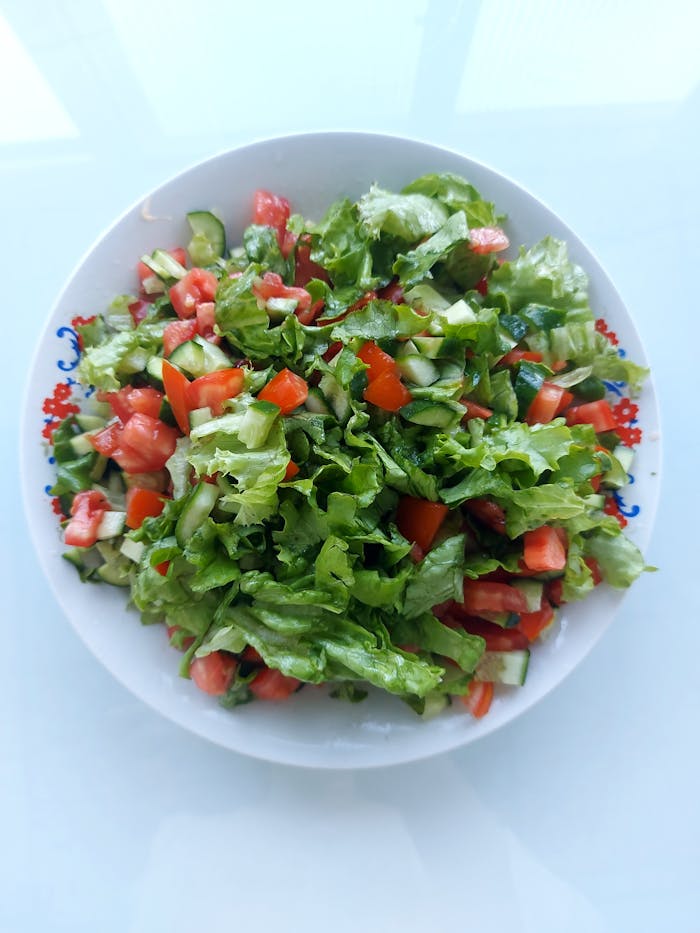 Colorful salad featuring lettuce, cucumber, and tomatoes on a decorative plate.