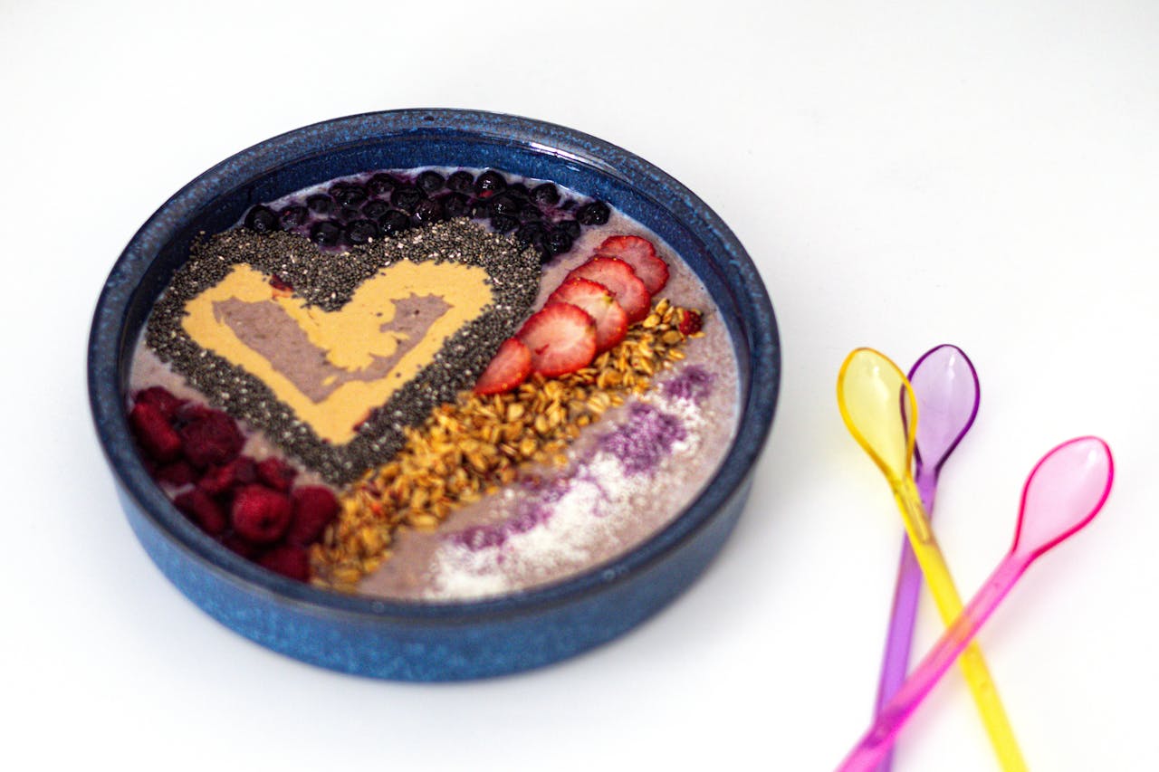 Vibrant smoothie bowl topped with fresh berries, chia seeds, and granola in a blue bowl.